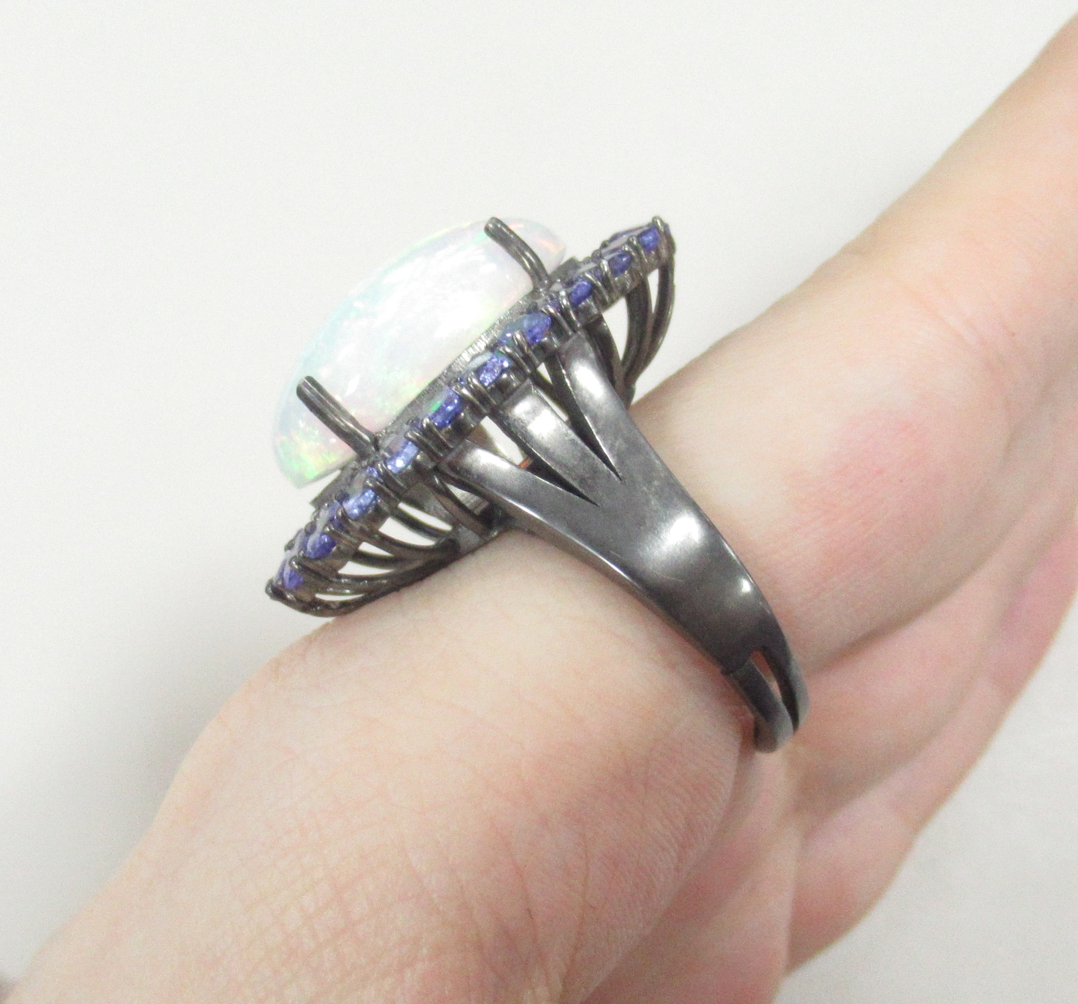 Серебряное кольцо 925 пробы; родий (бел.черн.); вставки 1 Опал бел. 10,5ct (Эфиопия); 24 Танзанит 4,04ct; 40 Бр.Кр-17 0,31ct 3/5;